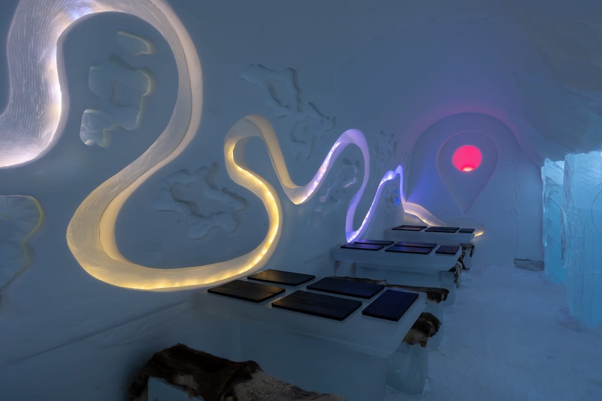 Visiting the Arctic SnowHotel in Rovaniemi
______

Inside the ice restaurant at an ice hotel with neon lights and reindeer hides on ice benches