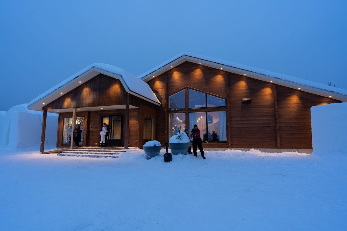 Visiting the Arctic SnowHotel in Rovaniemi
______

a dark blue sky with a wooden visitor center building with lights