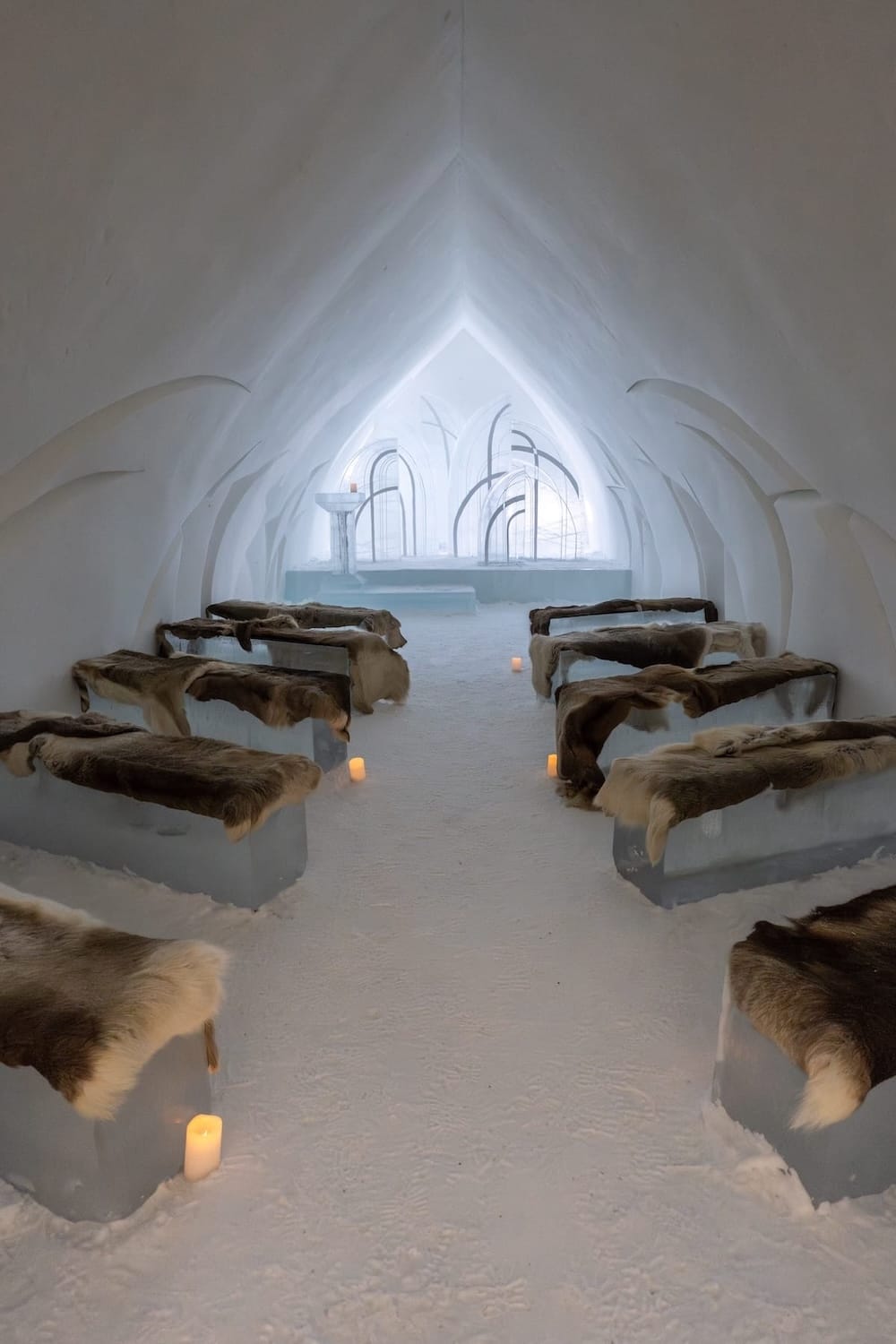 Visiting the Arctic SnowHotel in Rovaniemi
______

an ice chapel in an ice hotel with reindeer hides on the ice benches