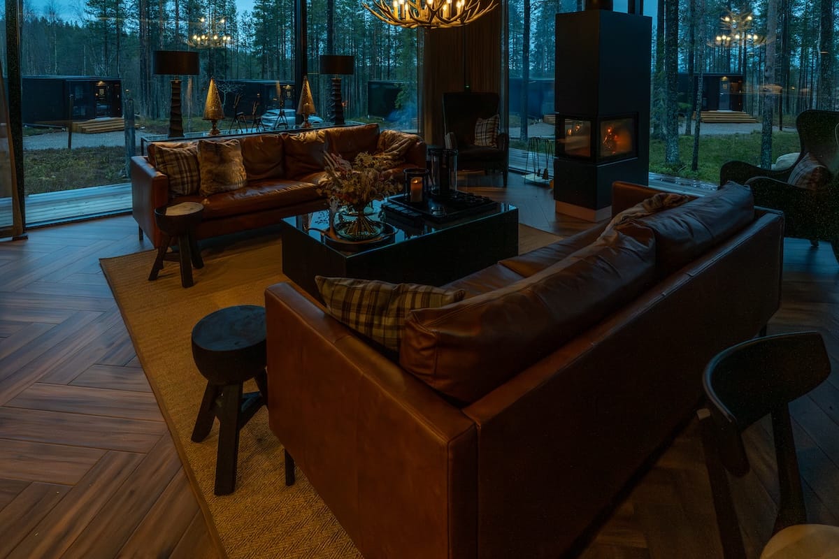 a large room with ceiling-to-floor windows with a fireplace and comfortable couches