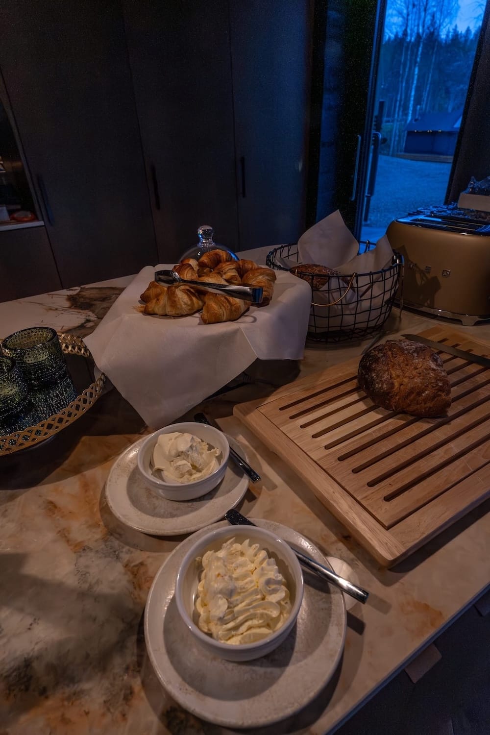 Half a loaf of bread, whipped butter, and croissants on a table