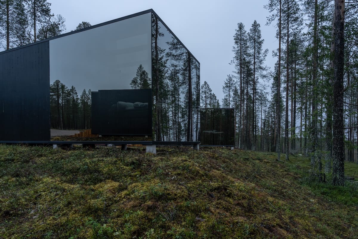 a reflective glass cabin in the middle of a finnish forest