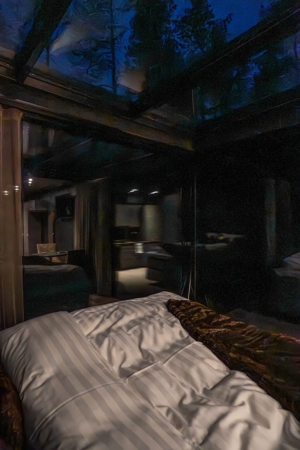a bed inside a black cabin with dark skies outside