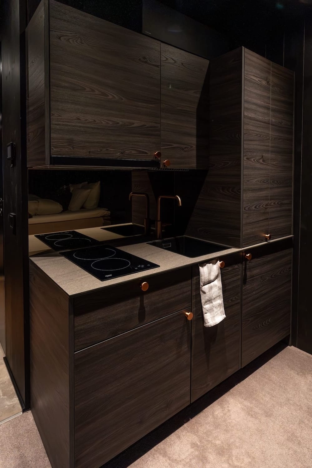a kitchenette area with cabinets and a tea towel inside a cabin