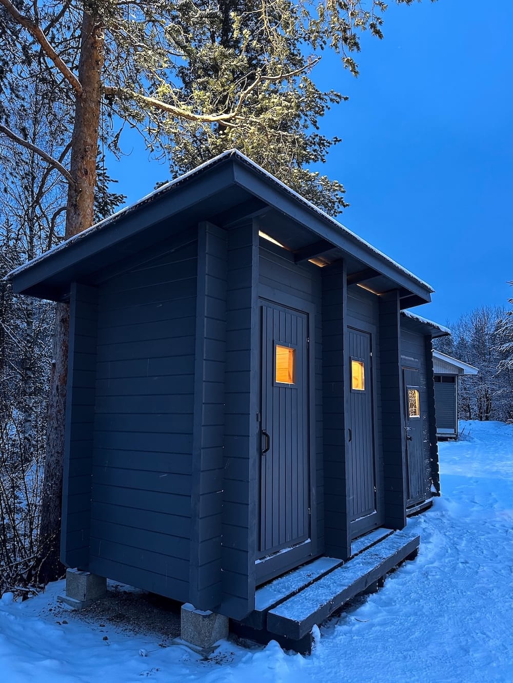 Ice karting in Rovaniemi | Santa's Motor Park
Wooden outdoor toilets with lights on.