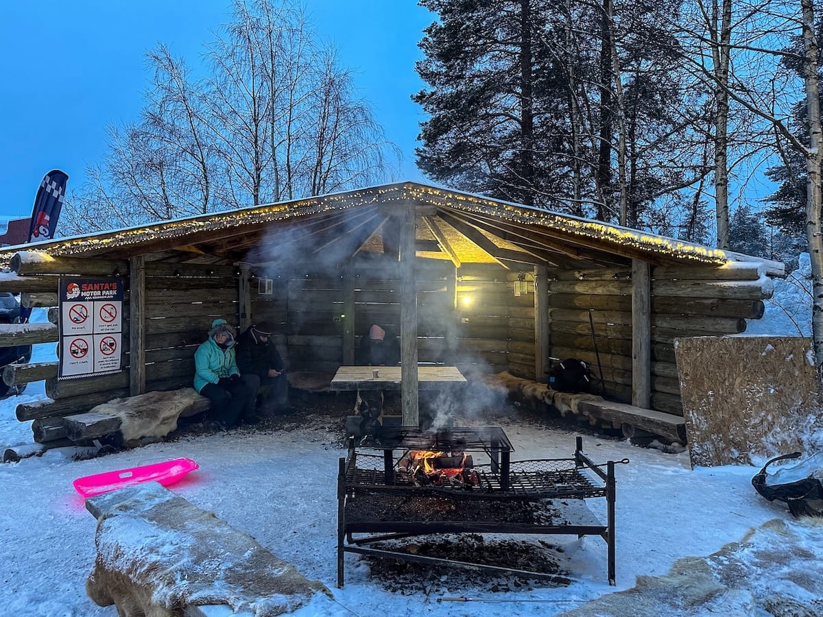 Ice karting in Rovaniemi | Santa's Motor Park
An outdoor fire with tourists gathered in a shelter with a pink sled to the side.