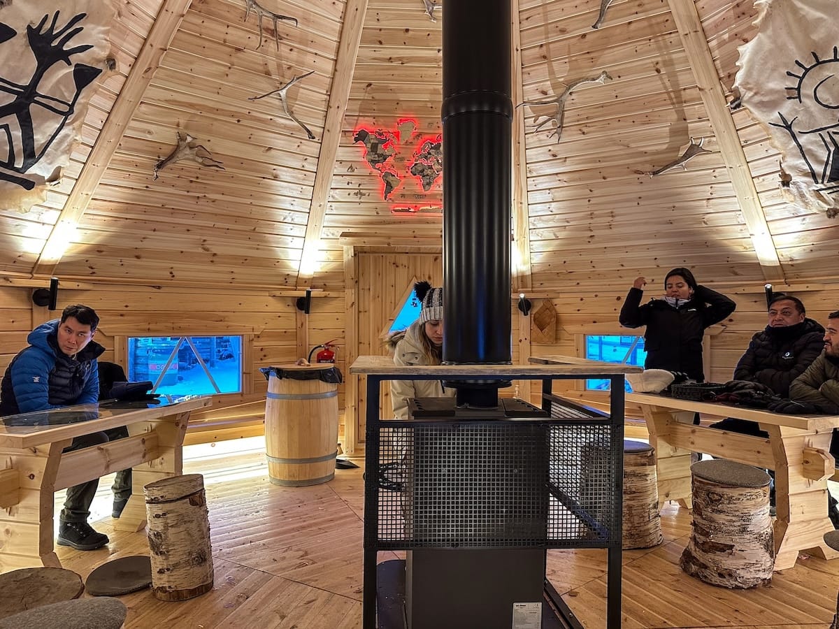 Ice karting in Rovaniemi | Santa's Motor Park
Inside of a wooden kota with tourists around a fire.