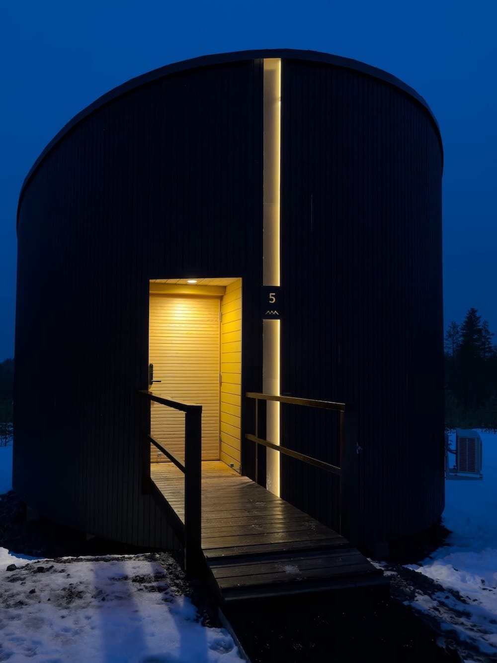 Livo Arctic Resort
_____
A photo of a black cabin with lighting and a door under a dark blue sky