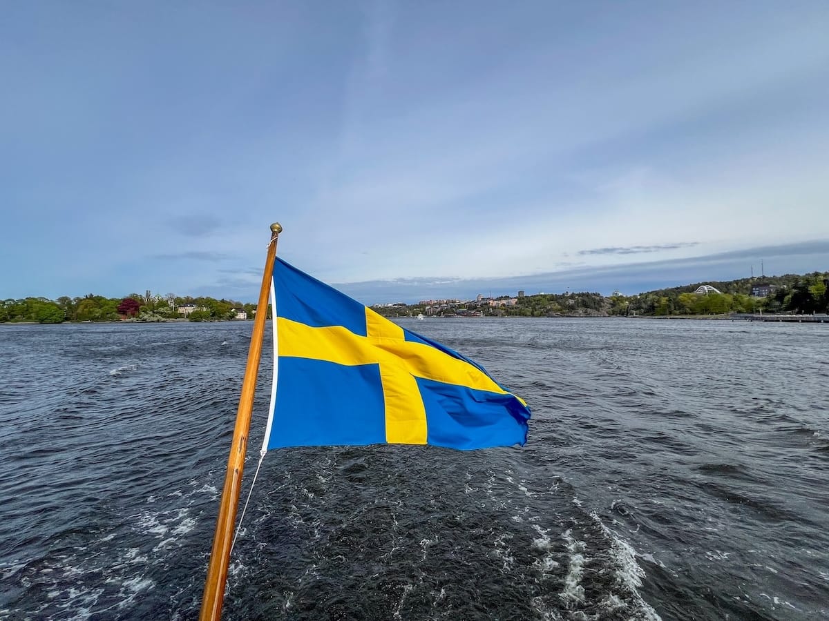 Stockholm archipelago boat tour guide
_____
A Swedish flag flying behind a boat in the water