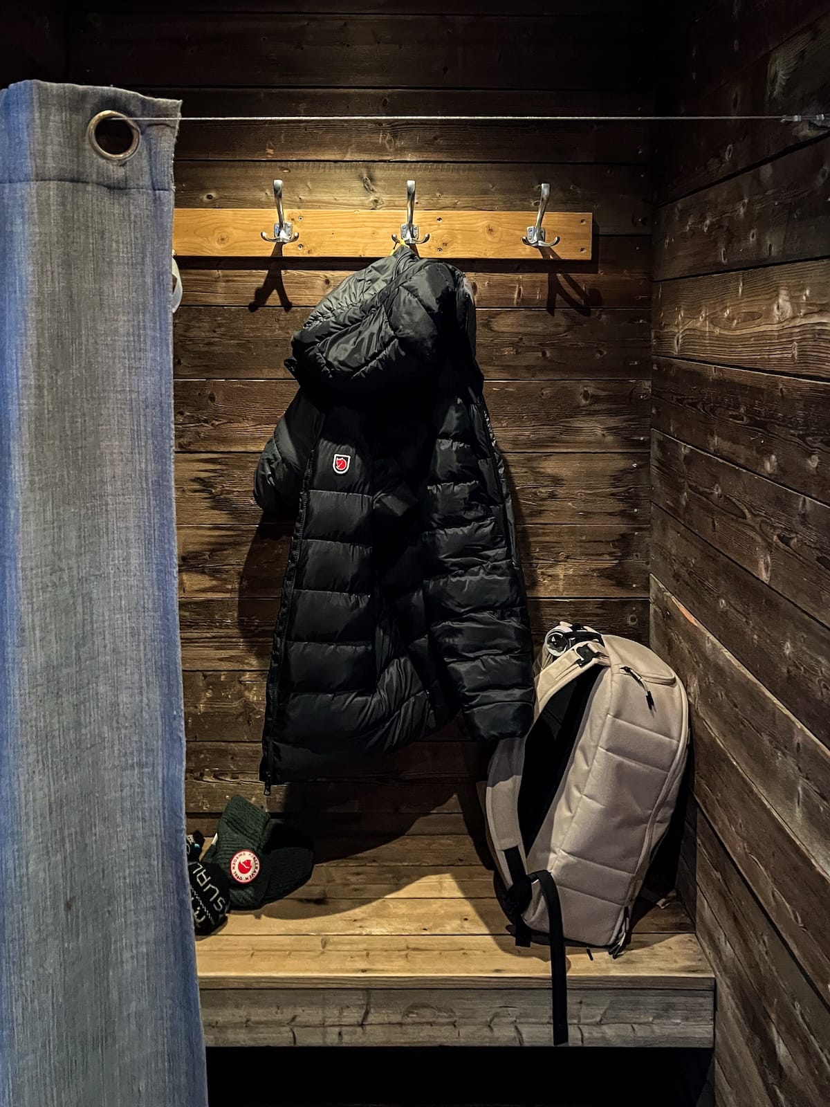 Visiting Svalbad Sauna in Svalbard
____
a wooden dressing room at a sauna where there is a jacket hanging and a backpack on a bench