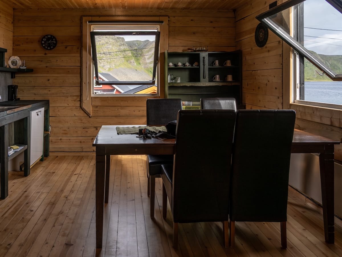 Where to Stay at the North Cape in Norway (+ Honningsvåg)
inside a wooden kitchen area with views out of the window to sea. a table and a kitchen is here