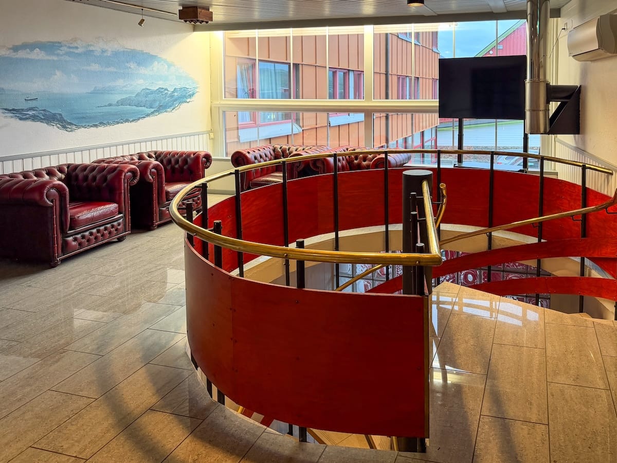 an outdated spiral staircase and painting on a wall inside a hotel's reception