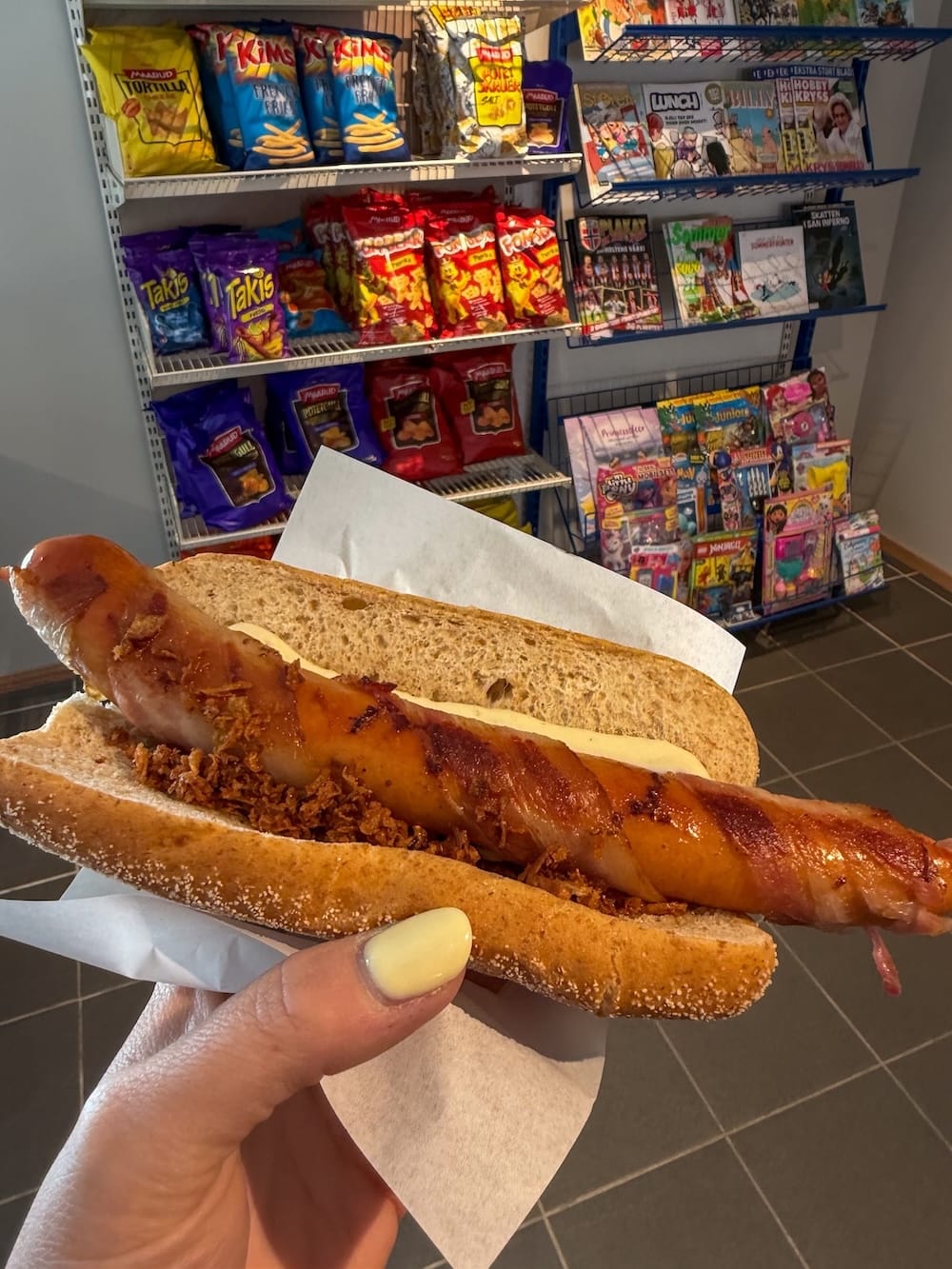 a hotdog in a women's hand in a shop