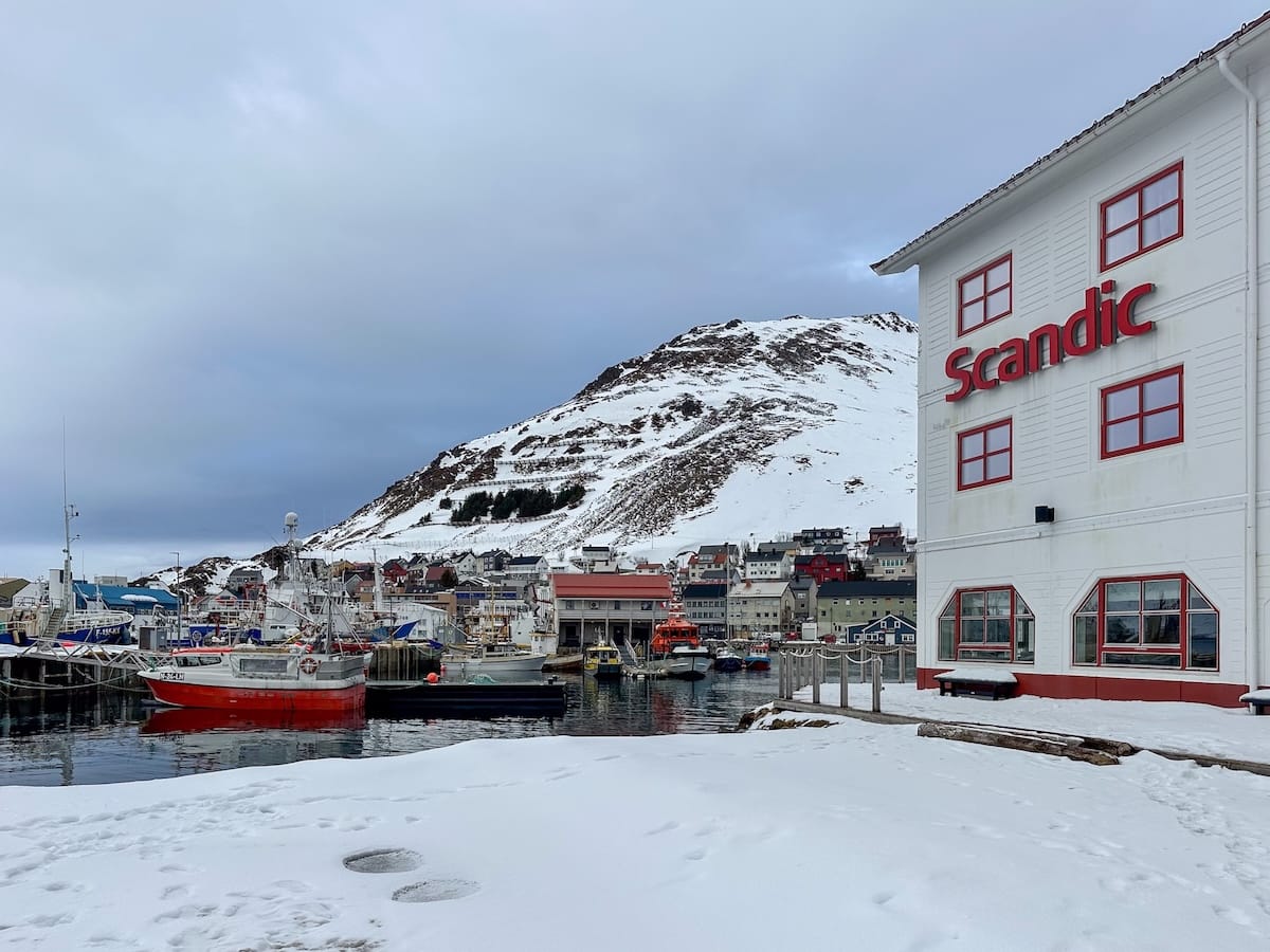 Where to Stay at the North Cape in Norway (+ Honningsvåg)
Scandic Bryggen Hotel - a white and red hotel on a harbor with a bunch of fishing boats in the snow