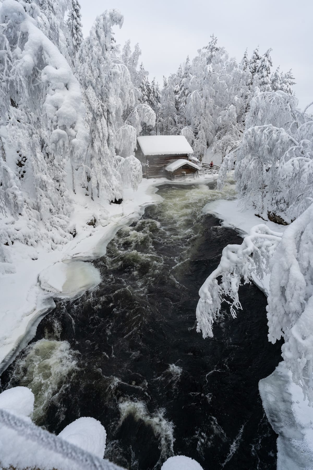 a photo of a mill along rapids in a snowy landscape
