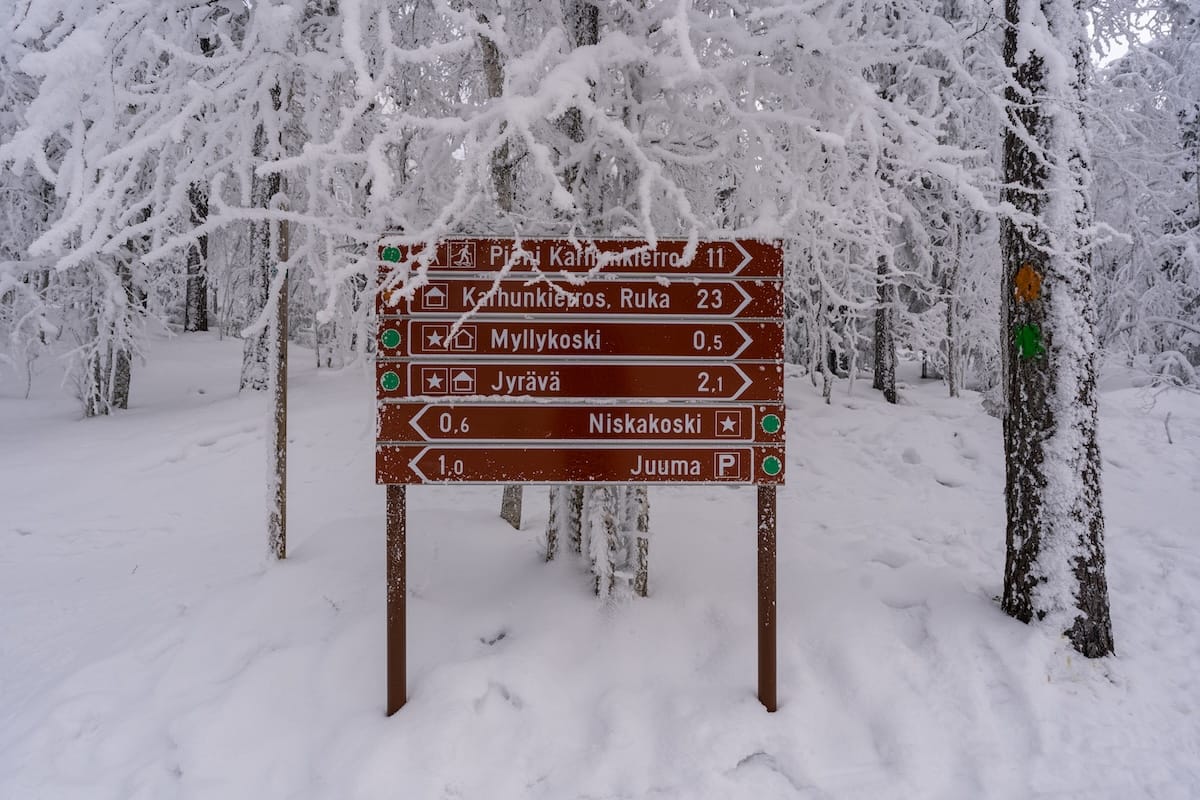 A brown sign on a snowy trail
