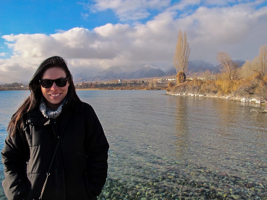 a woman in front of a clear lake in the mountains