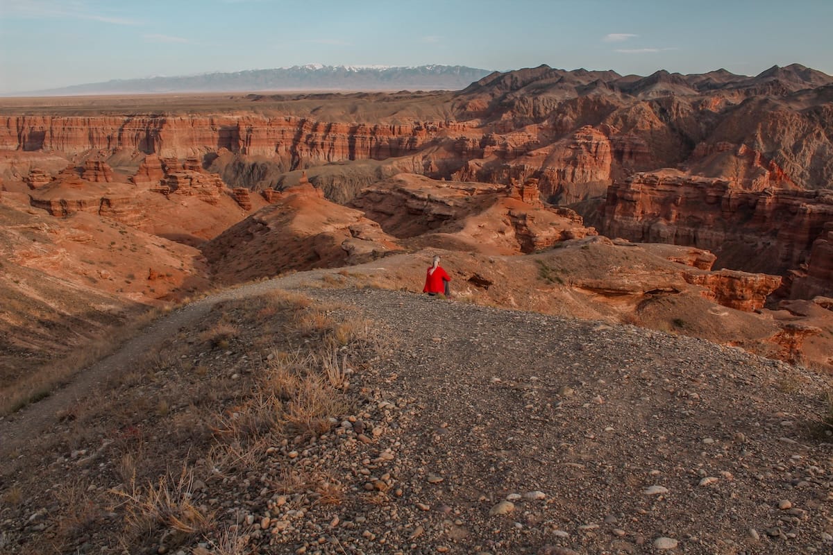 a canyon with a woman sitting on the edge of it