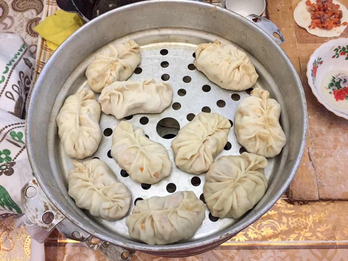 a bun of uncooked manti dumplings in a steamer pan