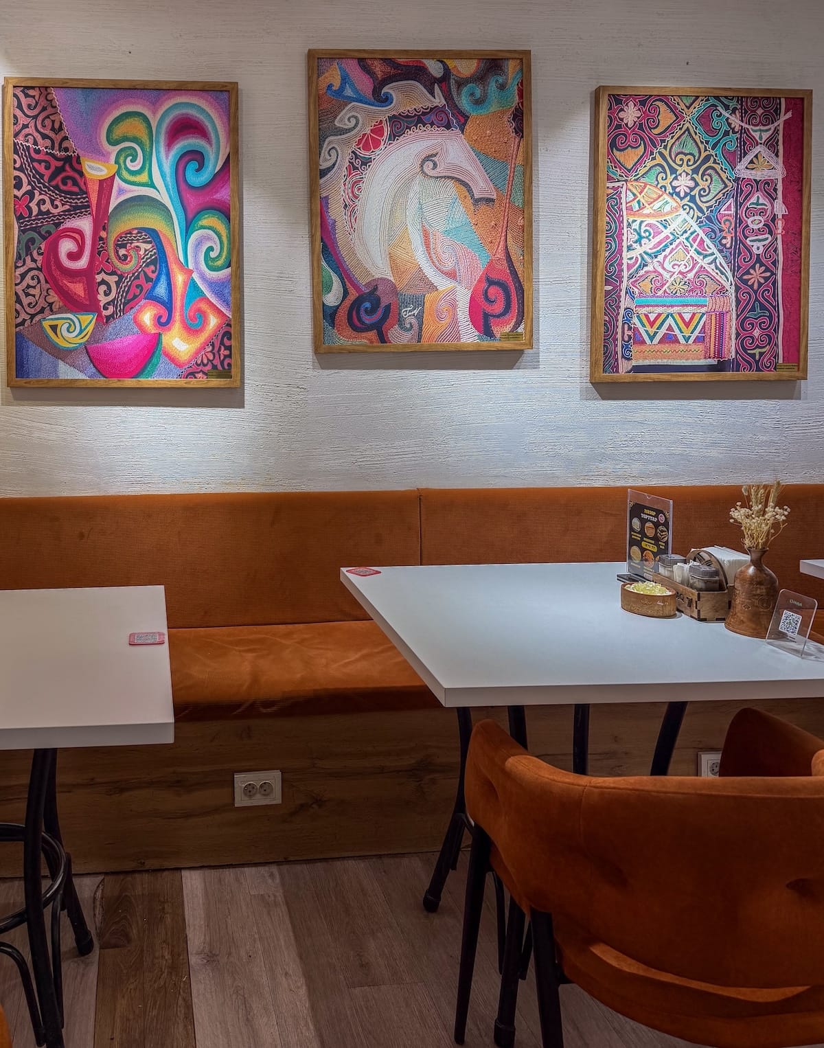 Inside a restaurant with tables and colorful paintings on the wall