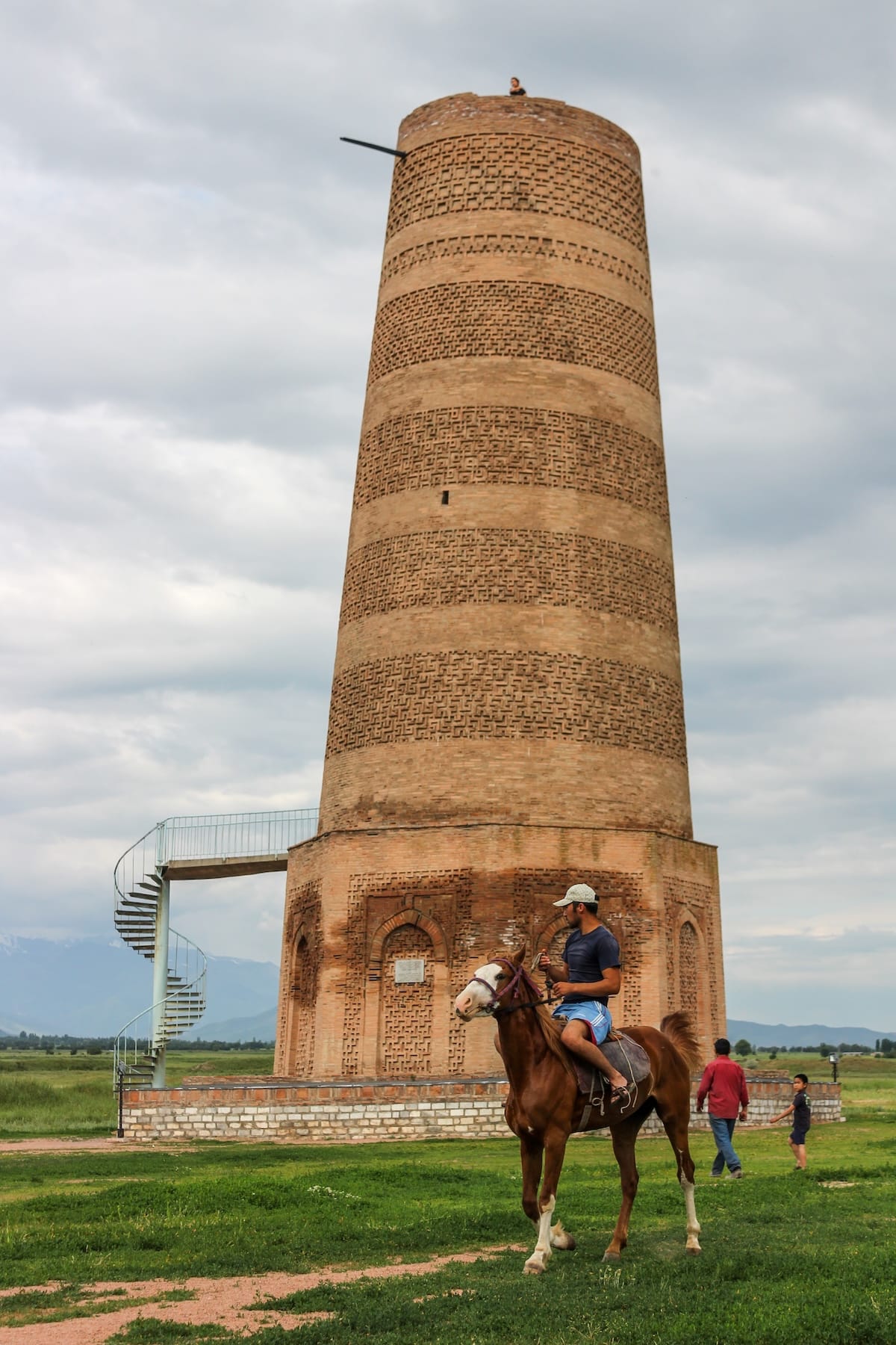 the burana tower with a man on a horse in front of it