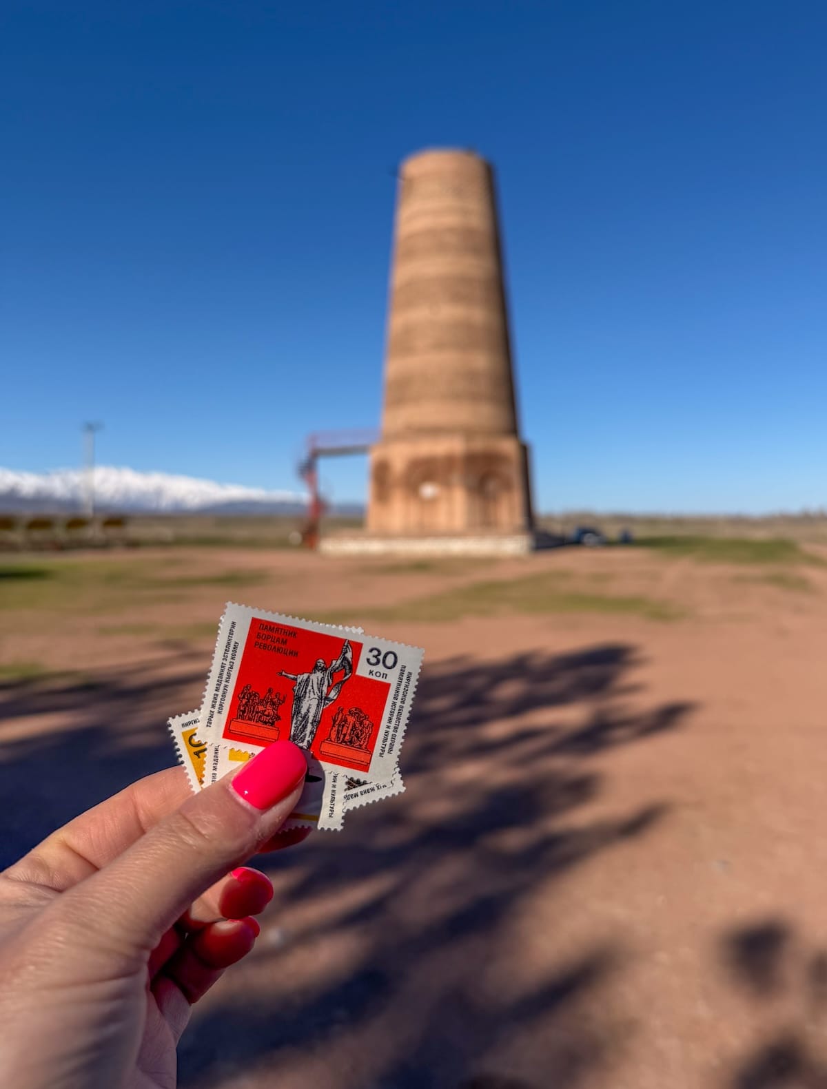 a woman holding stamp-like tickets in front of a tower
