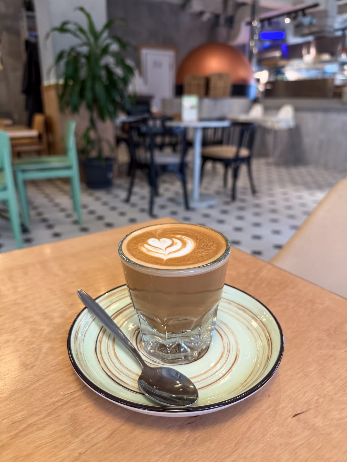 a flat white coffee on a table with a spoon in a mug