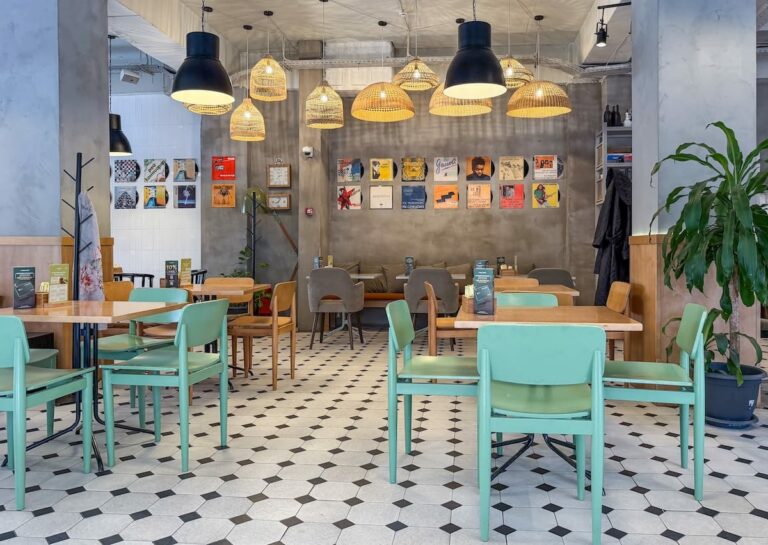 a photo of a modern looking cafe with colorful seating, artwork, and greenery