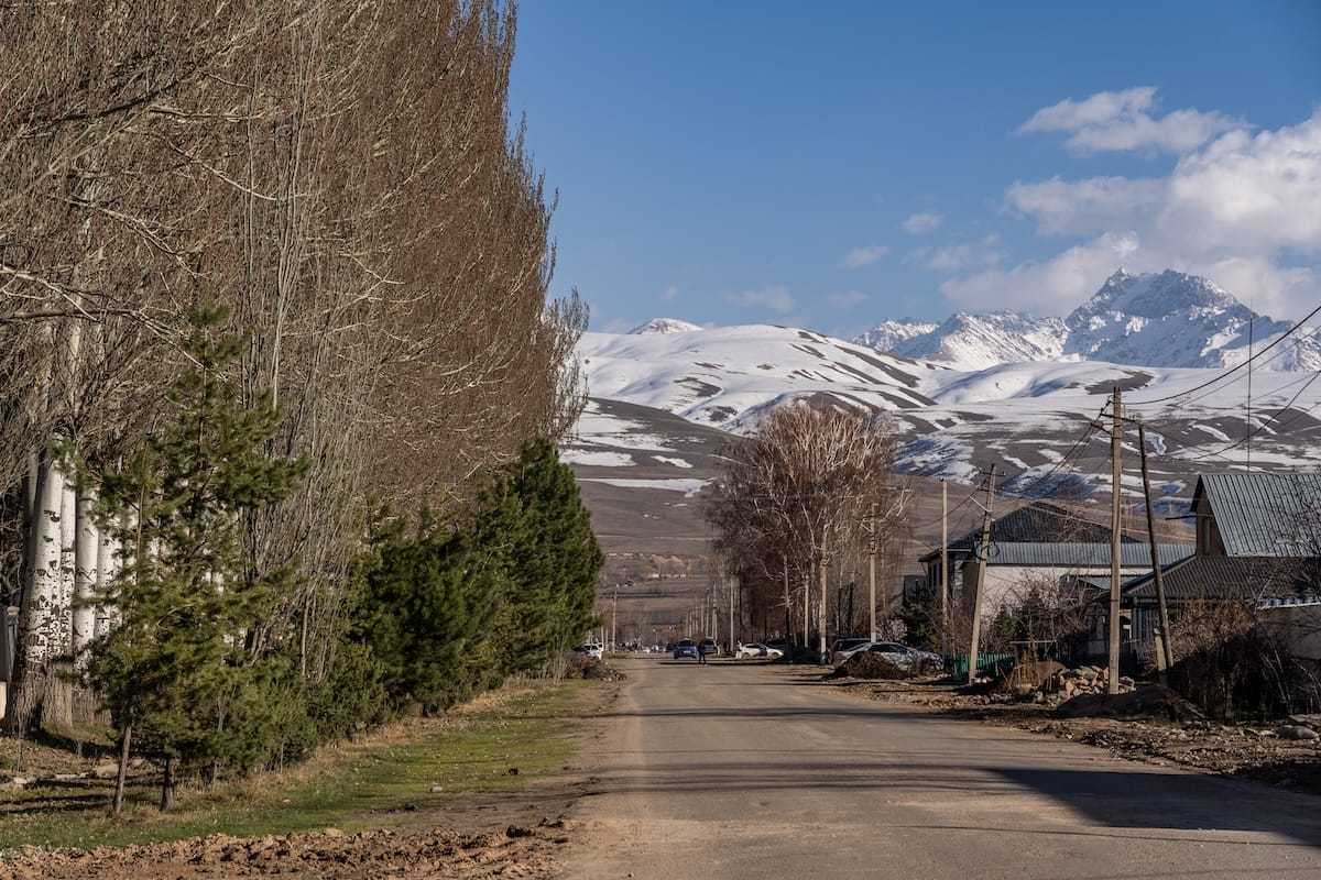 mountains at the end of a road with a little snow on them
