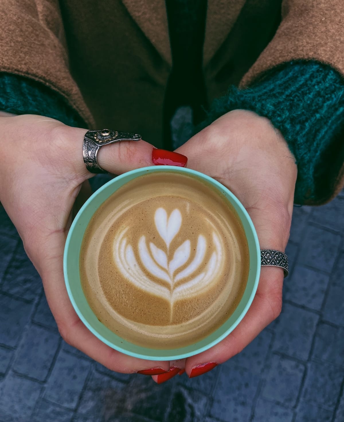 a woman's hand with a coffee and latte art on it