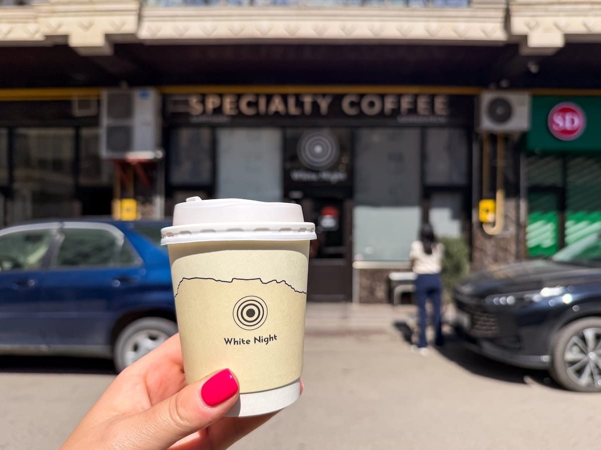 a woman's hand with a to-go coffee in it
