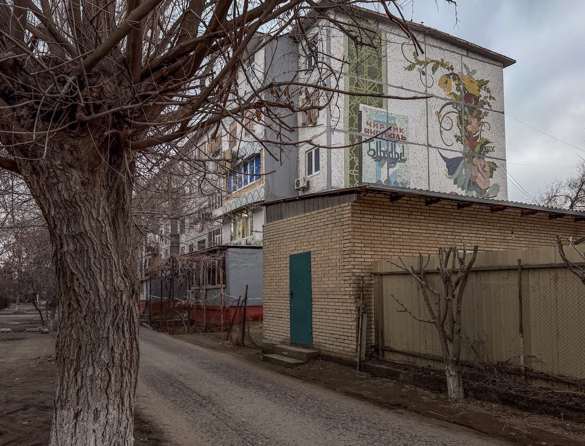 a mosaic on the side of a building with a tree in the foreground