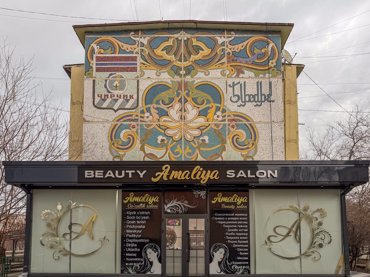 a soviet-era mosaic on a building with a salon beneath it