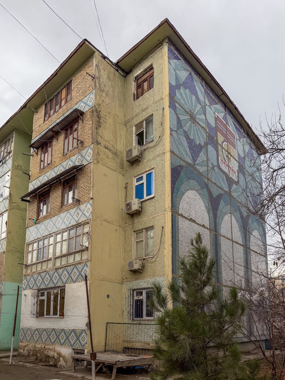 a mosaic on the side of a building with a lot of trees around