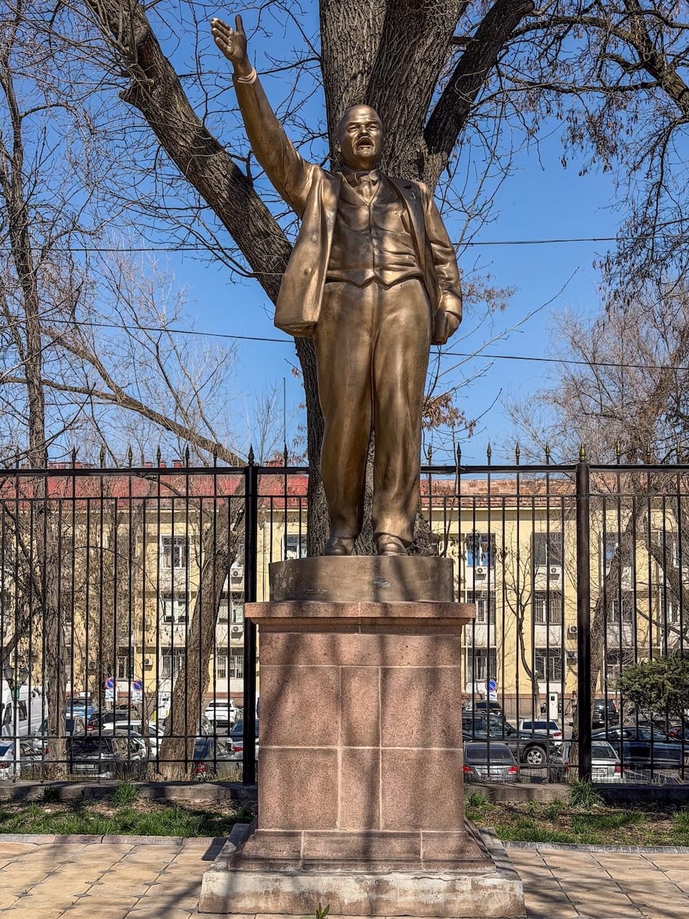 a gold lenin statue with a gate behind it