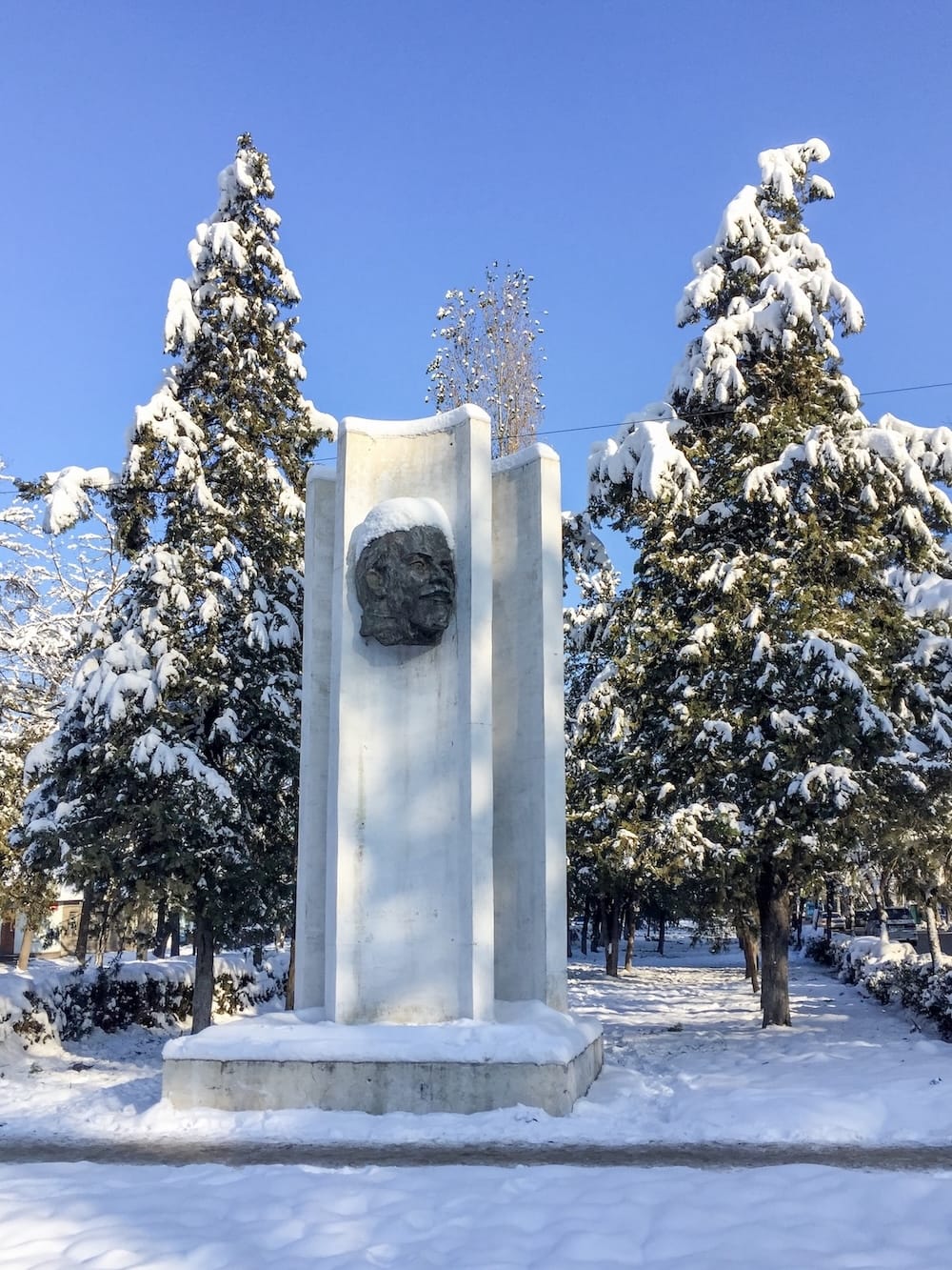 a monument of lenin in the snow with trees around it