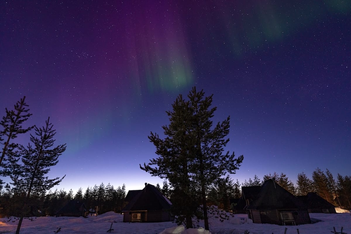 A photo of dim northern lights with light on the horizon