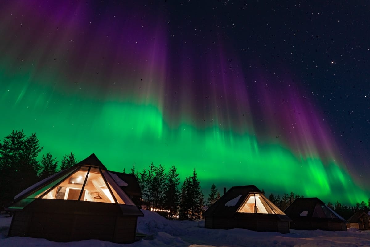 Two glass igloos under the aurora