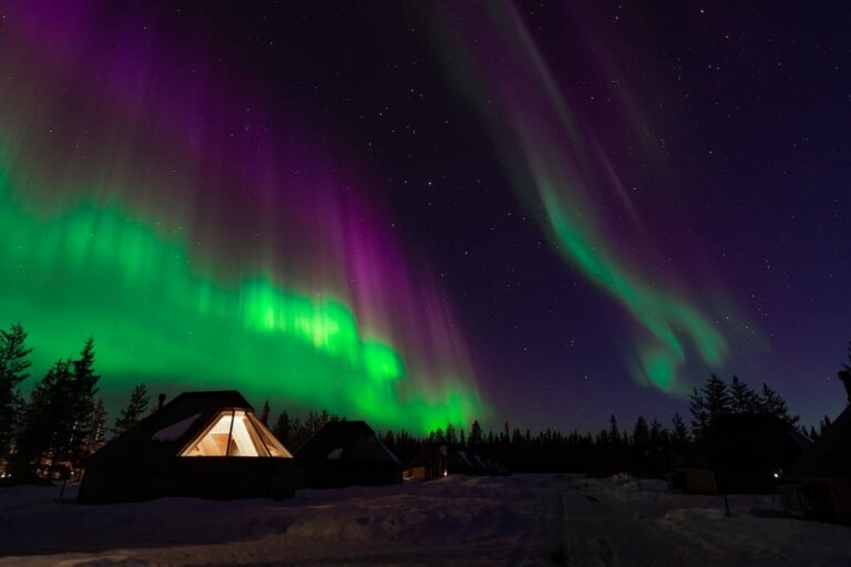a glass igloo hotel with northern lights overhead