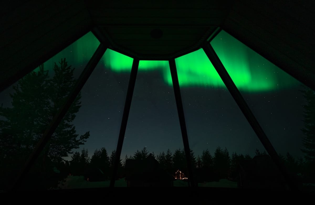an aurora overhead in a glass igloo