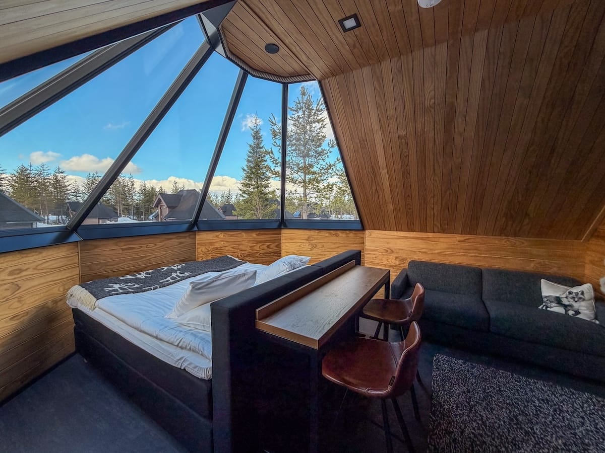 a glass igloo with a bed, bartop area, and a couch in it