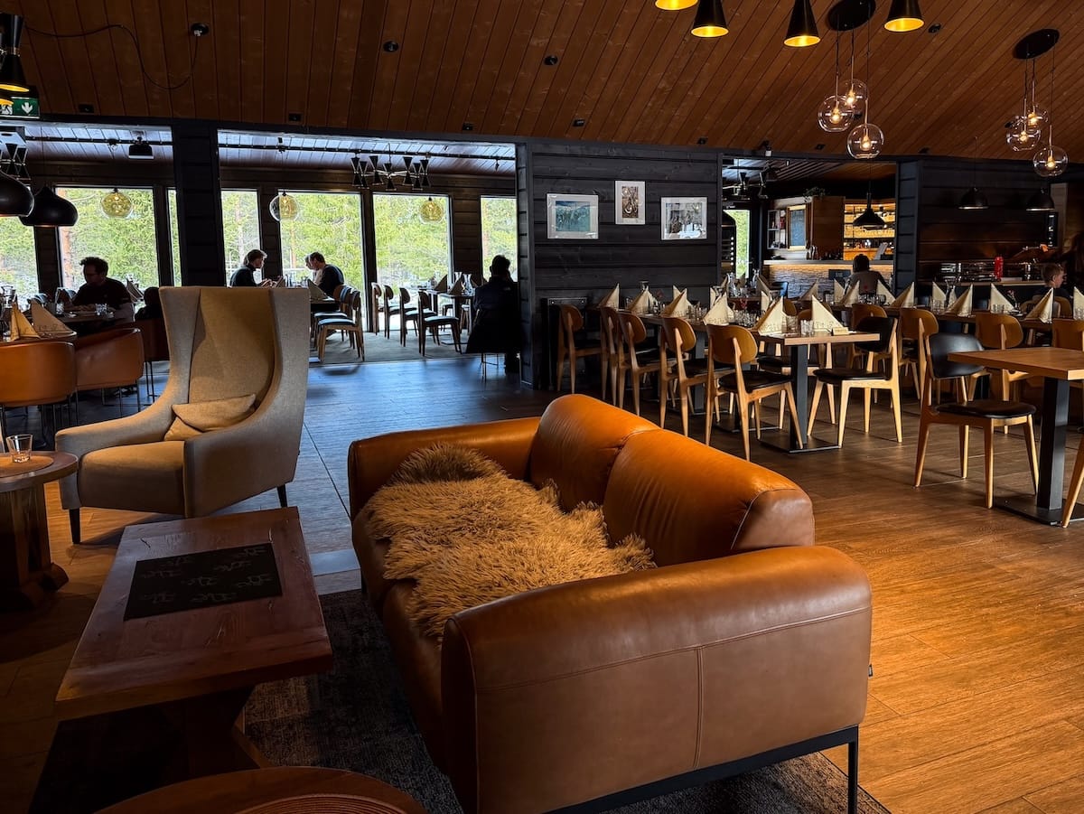 A leather couch with tables and chairs behind it in a restaurant