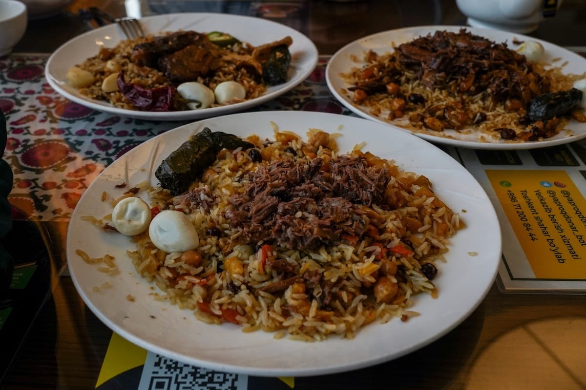 a table with three styles of plov on them; the one in the front has a quail egg on it