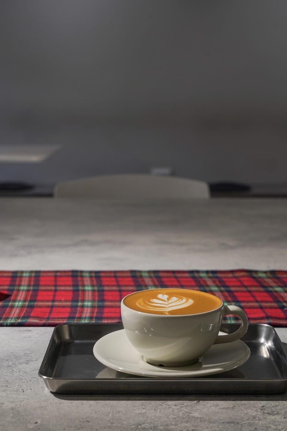 a flat white on a grey concrete table in a cafe