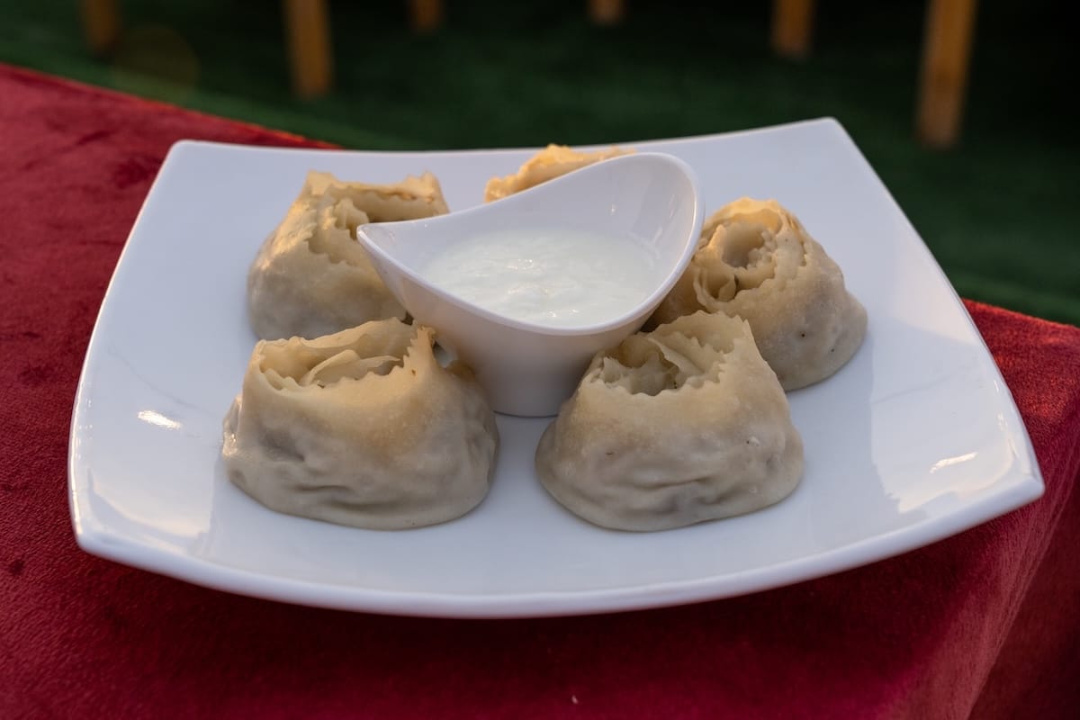 a plate of ghul khonim dumplings and sour cream on a table in a restaurant
