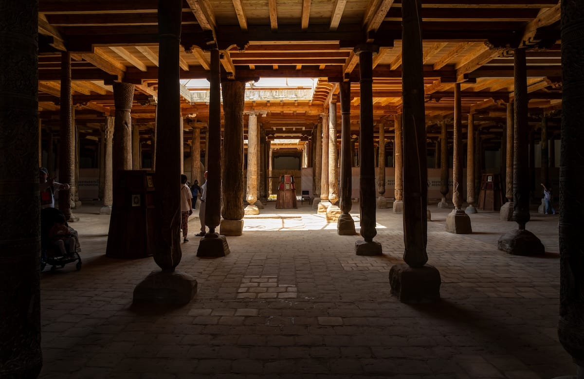 inside an old mosque that is dark with a lot of wooden columns (carved)