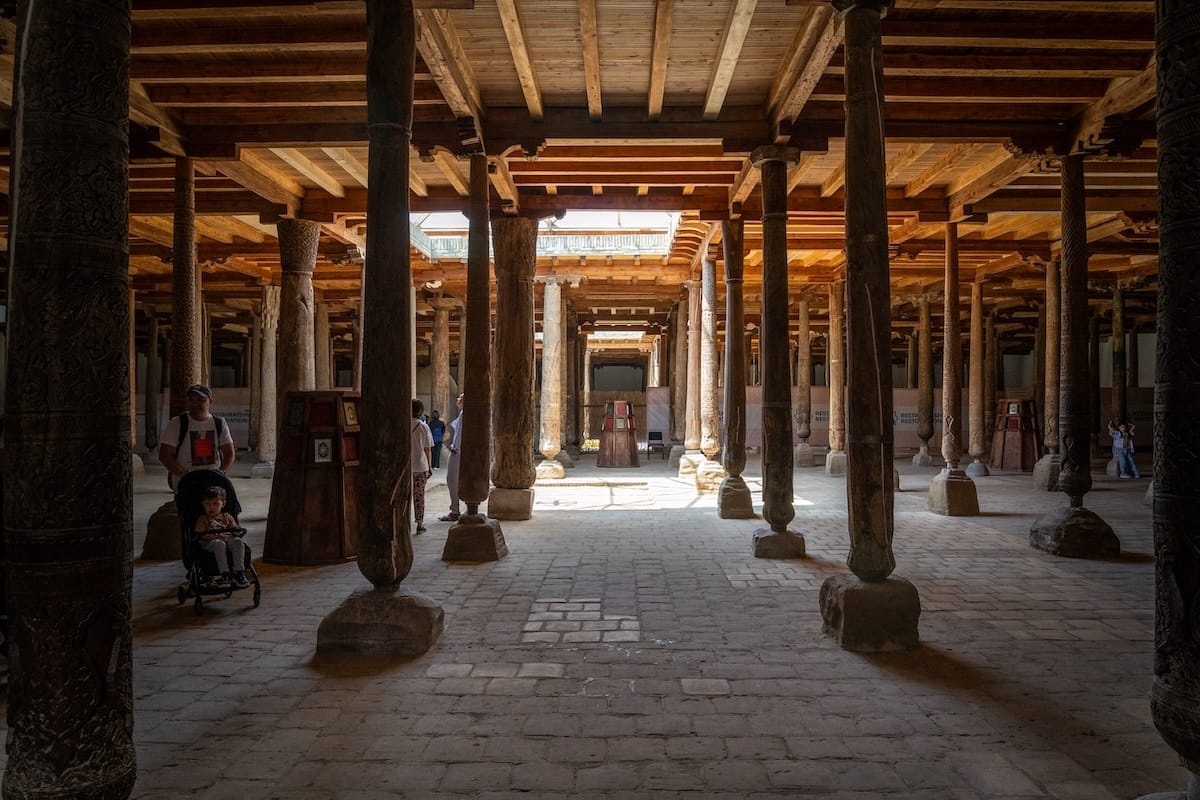 an old mosque with a lot of wooden pillars and sunlight coming through