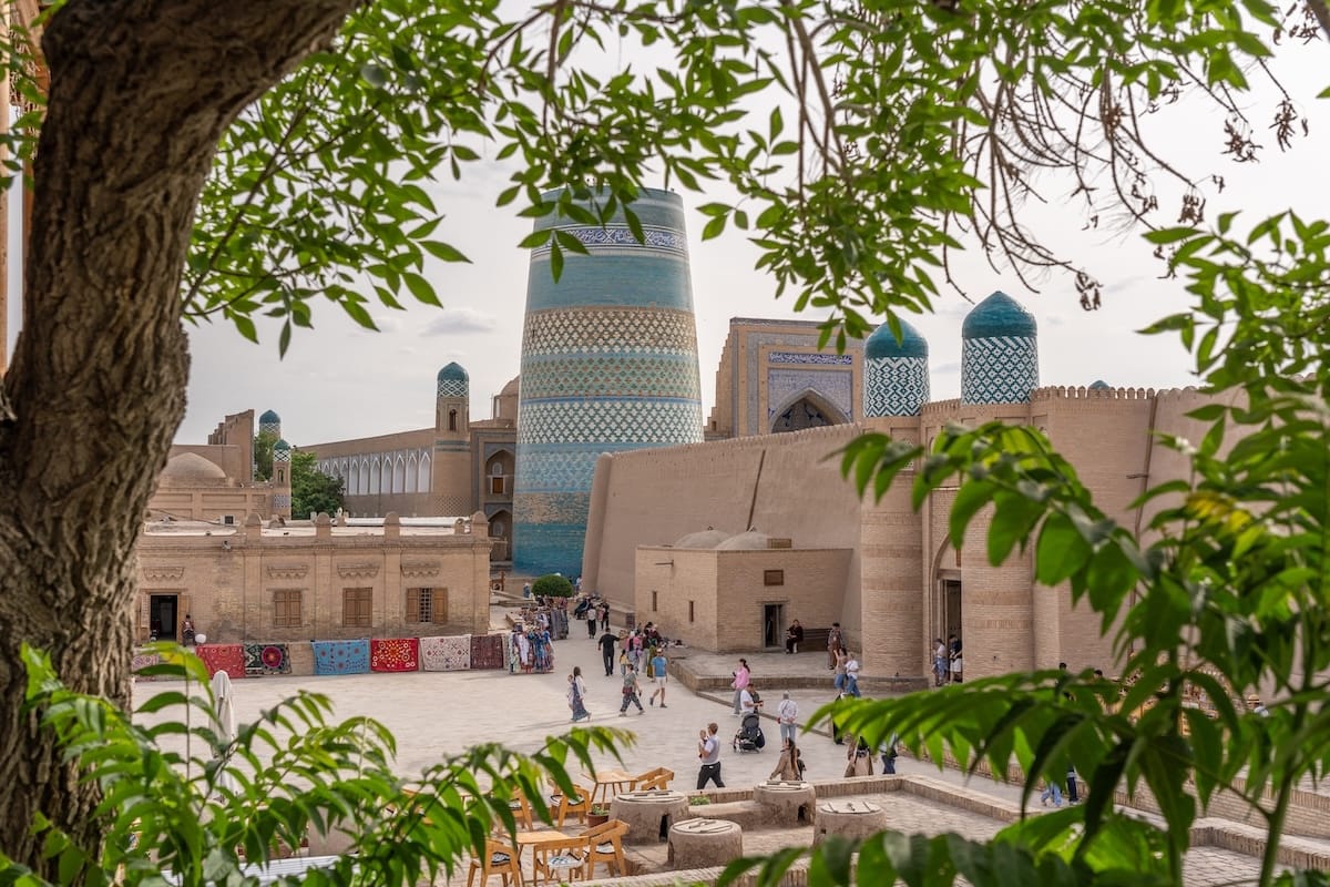 a photo with trees as framing of a famous blue minaret in khiva