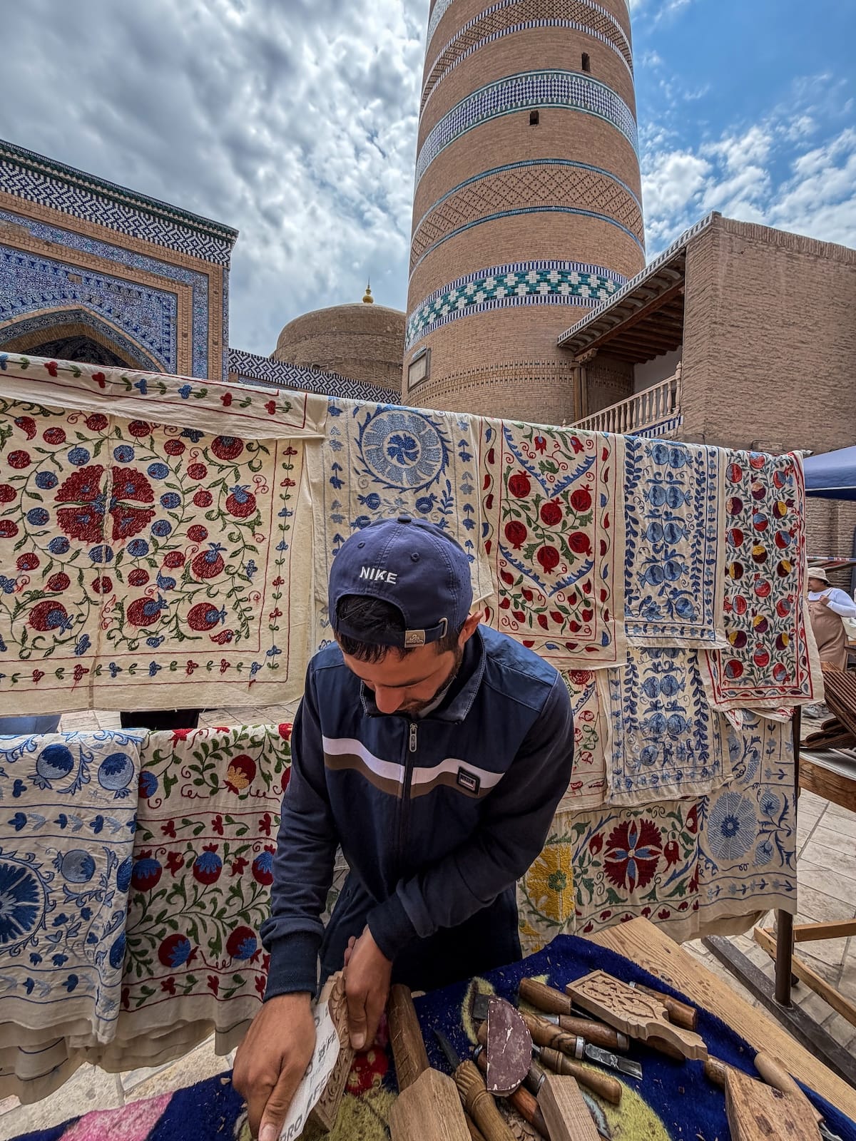 a man working in front of a minaret carving wood