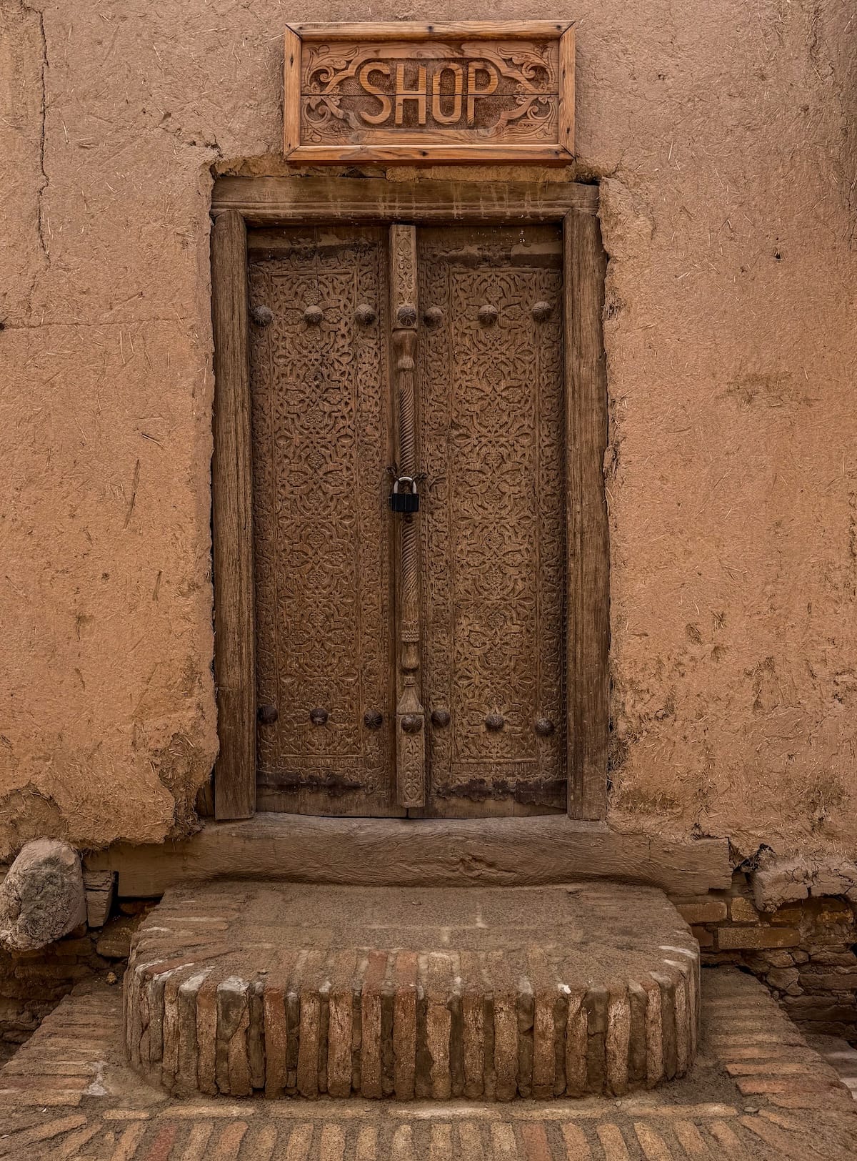 a wooden, carved door with a sign over it that says shops